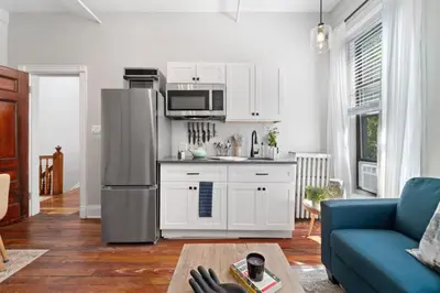 a kitchen with white cabinets and a blue couch at Newly Renovated 3BR Oasis Walk to Columbia Uni in New York