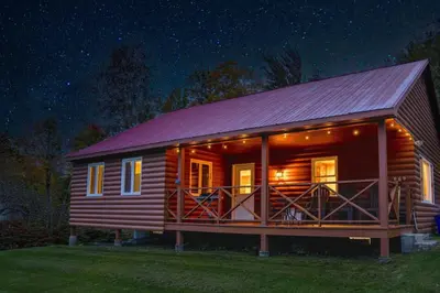 a log cabin with a red roof at night at Cozy Cabin in Stratton Mountain & Mount Snow 10min in Stratton