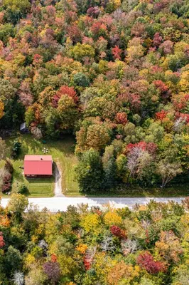 a red barn in the middle of a forest of trees at Cozy Cabin in Stratton Mountain & Mount Snow 10min in Stratton
