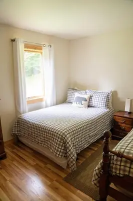 a bedroom with a bed with a plaid bedspread and a window at Cozy Cabin in Stratton Mountain & Mount Snow 10min in Stratton