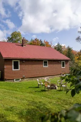 a cabin with chairs and a table in front of it at Cozy Cabin in Stratton Mountain & Mount Snow 10min in Stratton