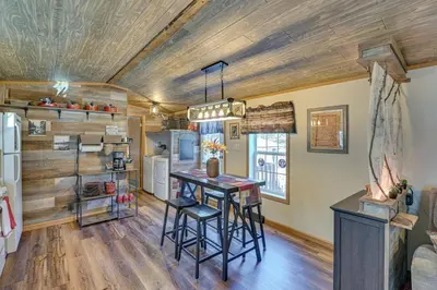 a kitchen with a wooden ceiling and a table with stools at Northville Cabin with Fire Pit, 4 Mi to Boat Ramp! in Northville