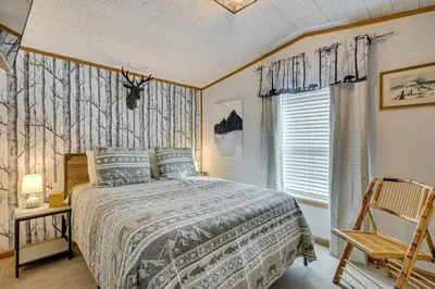 a bedroom with a bed and a chair and a window at Northville Cabin with Fire Pit, 4 Mi to Boat Ramp! in Northville