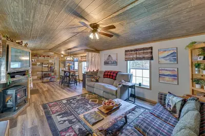 a living room with a couch and a ceiling fan at Northville Cabin with Fire Pit, 4 Mi to Boat Ramp! in Northville