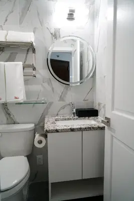a white bathroom with a toilet and a mirror at Starlight Hotel Near LGA Airport in Queens