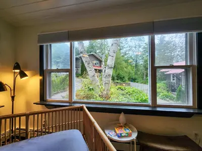 a bedroom with a large window with a tree at Belleayre Lodge in Pine Hill