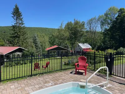 a hot tub next to a fence with two chairs at Belleayre Lodge in Pine Hill