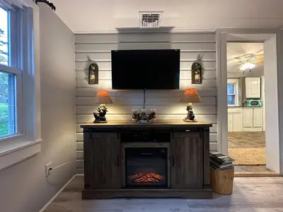 a living room with a fireplace with a flat screen tv at Escape to a Streamside Cabin in the Lower Catskills in Wurtsboro
