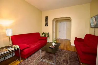 a living room with a red couch and a table at Tuk Ahoy - Indigo Suite (3A) with Shared Spaces in Brooklyn