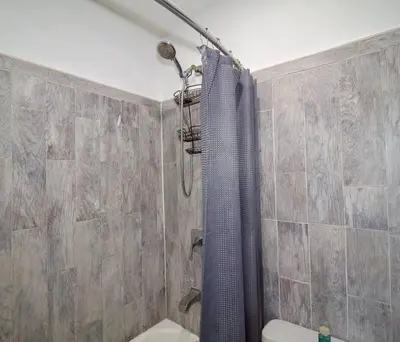 a bathroom with a shower with a blue shower curtain at Tuk Ahoy - Indigo Suite (3A) with Shared Spaces in Brooklyn
