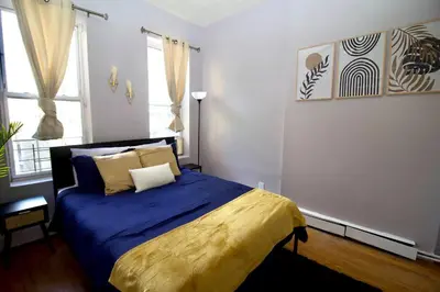 a bedroom with a bed with a blue and yellow blanket at Tuk Ahoy - Indigo Suite (3A) with Shared Spaces in Brooklyn