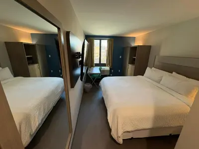 a bedroom with two beds and a mirror at Holiday Inn Express & Suites Bronx - Zoo Area by IHG in Bronx