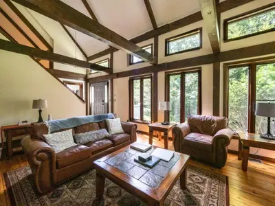 a living room with couches and a table and windows at Berkshire Vacation Rentals: Pristine Home In Becket Woods in Becket