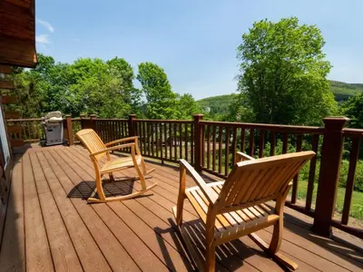 two chairs sitting on a wooden deck with a grill at Berkshire Vacation Rentals: Great Barrington Cabin Sleeps 14 Walk To Town in Great Barrington