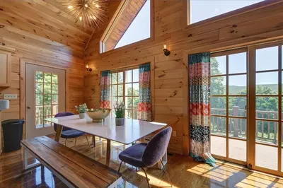 a dining room with a table and chairs and windows at Berkshire Vacation Rentals: Great Barrington Cabin Sleeps 14 Walk To Town in Great Barrington