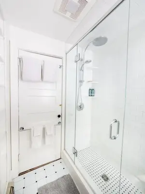 a white bathroom with a shower with a glass door at Classic Stockbridge Cottage in Stockbridge