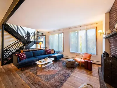 a living room with a blue couch and a staircase at Private Berkshires Home On 5+ Acres Rustic & Chic in Otis