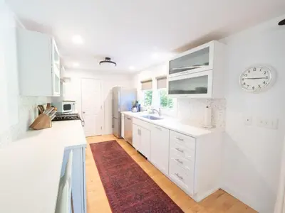 a kitchen with white cabinets and a clock on the wall at Berkshire Vacation Rental: Stockbridge Home Come Experience The Berkshires in Stockbridge