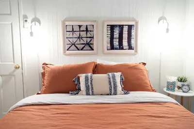 a bed with an orange and white pillow on it at Berkshire Vacation Rentals: Great Barrington Walkable To Lake And Town in Great Barrington