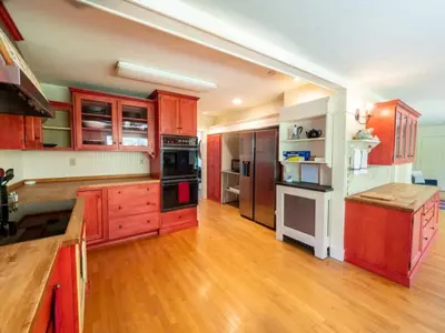 a large kitchen with wooden cabinets and wooden floors at Berkshire Vacation Rentals: Renovated Five Bedrooms In Historic Williamstown in Williamstown