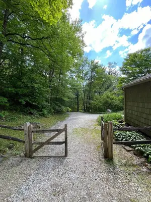 a gate on a dirt road next to a house at Berkshire Vacation Rentals: Chic Pittsfield Home With A View in Pittsfield