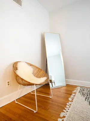 a wicker chair sitting in front of a mirror at Berkshire Vacation Rentals: Chic Pittsfield Home With A View in Pittsfield