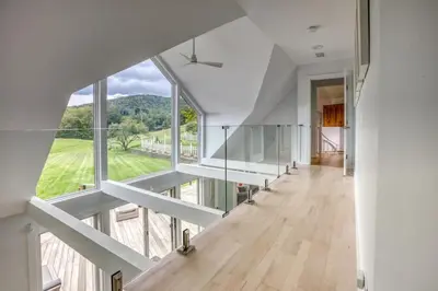 a large white room with a large window and a hallway at Berkshire Vacation Rentals: The Brookman: Renovated 6000 SF Estate On 40 Acres in Williamstown