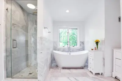 a white bathroom with a tub and a shower at Berkshire Vacation Rentals: The Brookman: Renovated 6000 SF Estate On 40 Acres in Williamstown