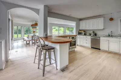 a kitchen with white cabinets and a wooden counter top at Berkshire Vacation Rentals: The Brookman: Renovated 6000 SF Estate On 40 Acres in Williamstown