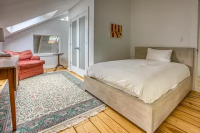 a bedroom with a bed and a living room at Berkshire Vacation Rentals: The Brookman: Renovated 6000 SF Estate On 40 Acres in Williamstown