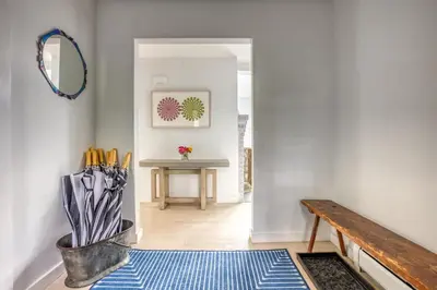 a hallway with a bench and a table with umbrellas at Berkshire Vacation Rentals: The Brookman: Renovated 6000 SF Estate On 40 Acres in Williamstown