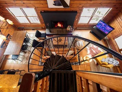 a spiral staircase in a living room with a fireplace at Berkshire Vacation Rentals: Private Cabin On Over 12 Acres Of Woods in Becket