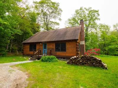 a cabin in the woods with a pile of logs at Berkshire Vacation Rentals: Private Cabin On Over 12 Acres Of Woods in Becket