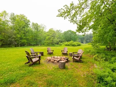 a group of chairs sitting around a fire pit at Berkshire Vacation Rentals: Private Cabin On Over 12 Acres Of Woods in Becket