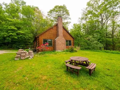 a log cabin with a picnic table in the grass at Berkshire Vacation Rentals: Private Cabin On Over 12 Acres Of Woods in Becket