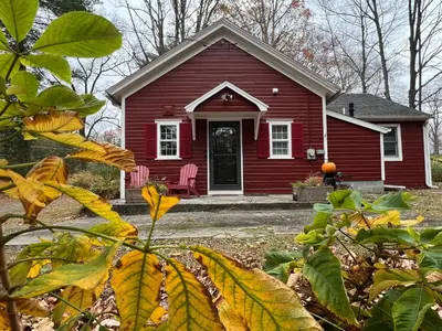 a red house with a chair in front of it at Schoolhouse No. 11 * Hudson Valley Upstate Getaway in Stone Ridge