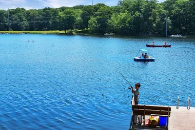a boy is standing on the end of a boat in the water at Lakefront, Pool, Hot Tub, Boats, Game Room, Pets in Bushkill