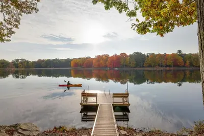 a person in a canoe on a dock on a lake at Lakefront, Pool, Hot Tub, Boats, Game Room, Pets in Bushkill