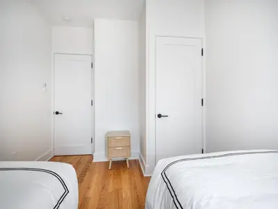 a white bedroom with two beds and a night stand at Modern Three Bedroom Brooklyn Condo-Hotel in Brooklyn