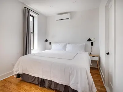 a white bed in a white bedroom with a window at Modern Three Bedroom Brooklyn Condo-Hotel in Brooklyn