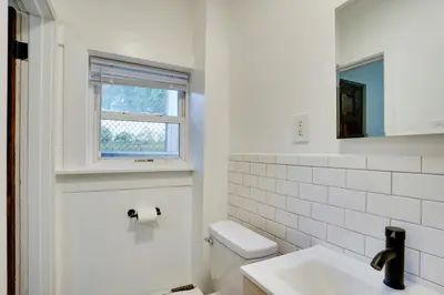 a white bathroom with a toilet and a window at Modern Hastings-On-Hudson Home Near River! in Hastings-on-Hudson