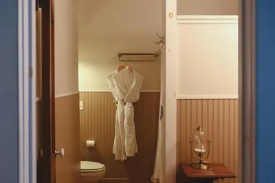 a bathroom with a toilet and a robe hanging on the wall at The North Branch Inn in North Branch