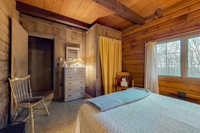 a bedroom with a bed and a dresser and a window at Log Ski Lodge in Wilmington
