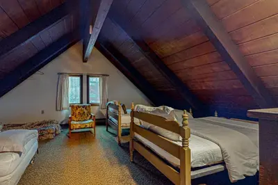 a attic bedroom with two beds and a chair at Log Ski Lodge in Wilmington