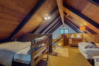 a attic bedroom with two beds and a desk at Log Ski Lodge in Wilmington