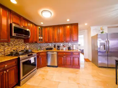 a kitchen with wooden cabinets and a stainless steel refrigerator at Stylish 3 bed, minutes to NYC! in Jersey City
