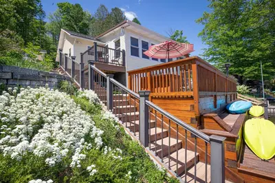 a house with a deck with an umbrella and a surfboard at Sunset Cottage #3 in Hamilton