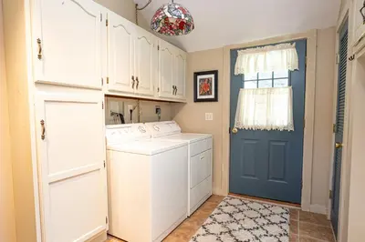 a laundry room with white cabinets and a blue door at Sunset Cottage #3 in Hamilton