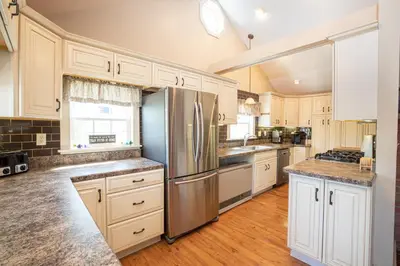 a kitchen with white cabinets and a stainless steel refrigerator at Sunset Cottage #3 in Hamilton