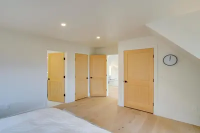 an attic bedroom with three doors and a clock at Brand New Luxury Ski Cabin - 2 Mi to Windham Mtn! in Windham